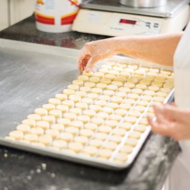 Microempresa - mulher coloca biscoitos em tabuleiro para assar